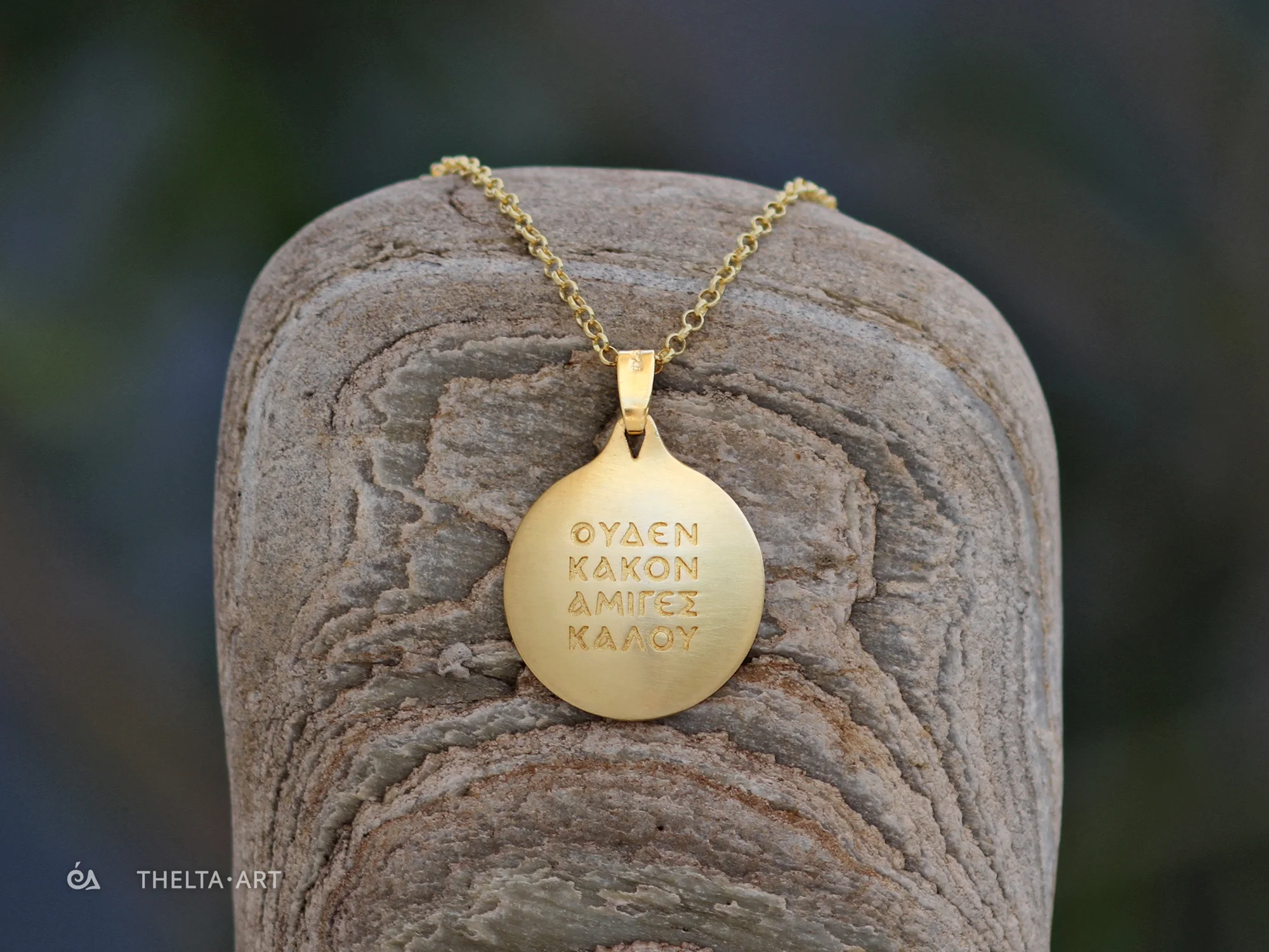 "Uden Kakon Amiges Kalou" - a handmade, gold-plated 925 silver pendant and chain with colorless script.